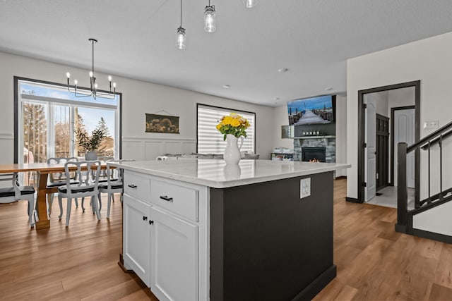 kitchen with pendant lighting, light wood finished floors, a center island, and white cabinets