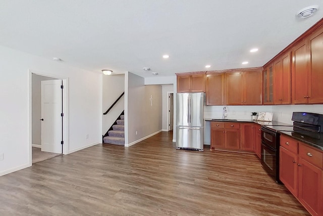 kitchen featuring wood finished floors, freestanding refrigerator, double oven range, dark countertops, and glass insert cabinets