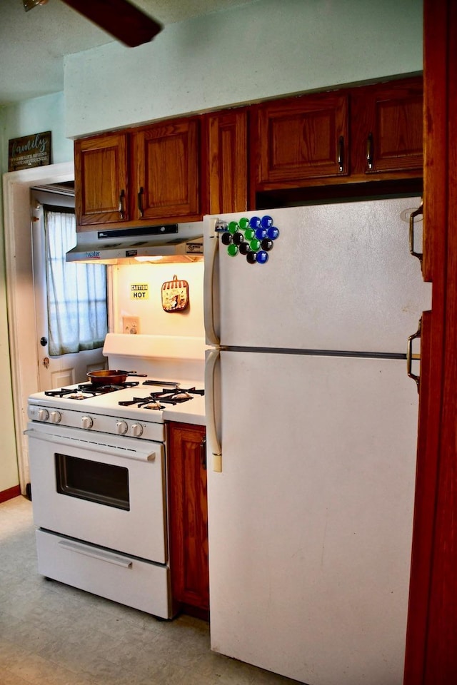 kitchen with white appliances, under cabinet range hood, and light countertops