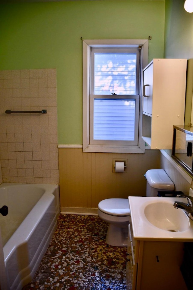 full bathroom with toilet, wainscoting, vanity, and a tub