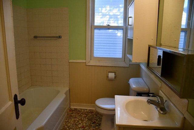 bathroom featuring toilet, a wealth of natural light, a sink, and a wainscoted wall