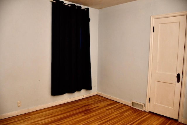 spare room with visible vents, baseboards, and wood finished floors