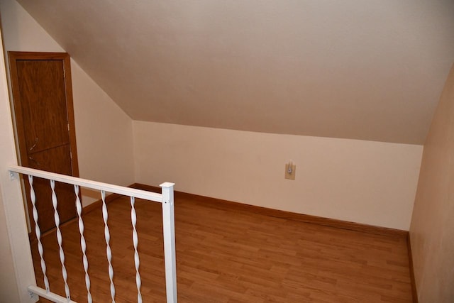 additional living space featuring baseboards, vaulted ceiling, and wood finished floors