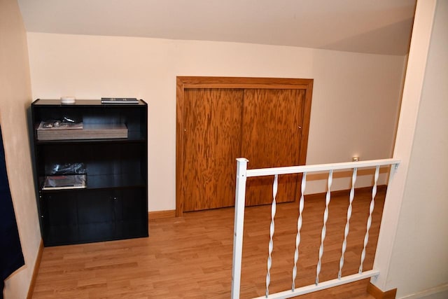 corridor with an upstairs landing, light wood-style flooring, and baseboards