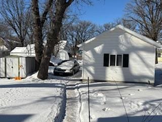 snow covered property featuring a shed and an outdoor structure