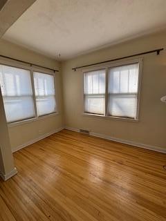 unfurnished room with light wood-style flooring, visible vents, and baseboards