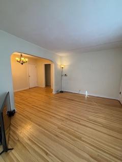 unfurnished living room featuring light wood-style floors and arched walkways