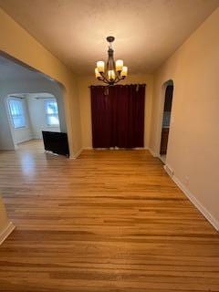 unfurnished dining area with light wood finished floors and a notable chandelier