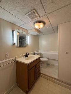 full bathroom with toilet, a paneled ceiling, vanity, and visible vents