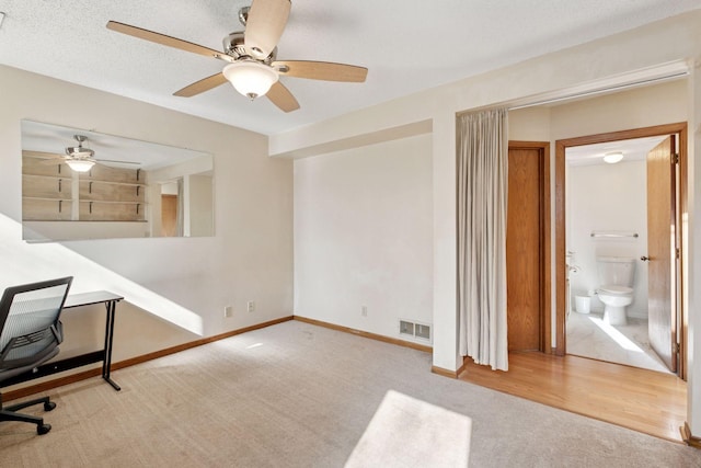 carpeted office space featuring visible vents, a textured ceiling, and baseboards