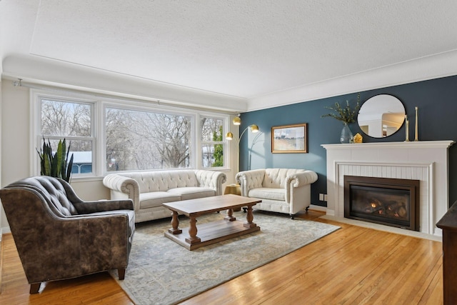 living room featuring a brick fireplace, a textured ceiling, and hardwood / wood-style floors