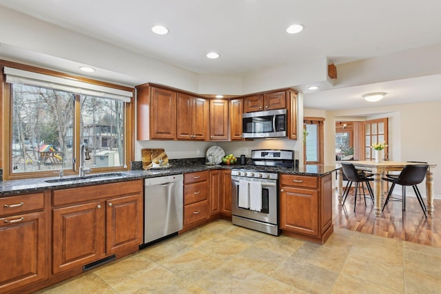 kitchen featuring sink, kitchen peninsula, appliances with stainless steel finishes, and dark stone counters