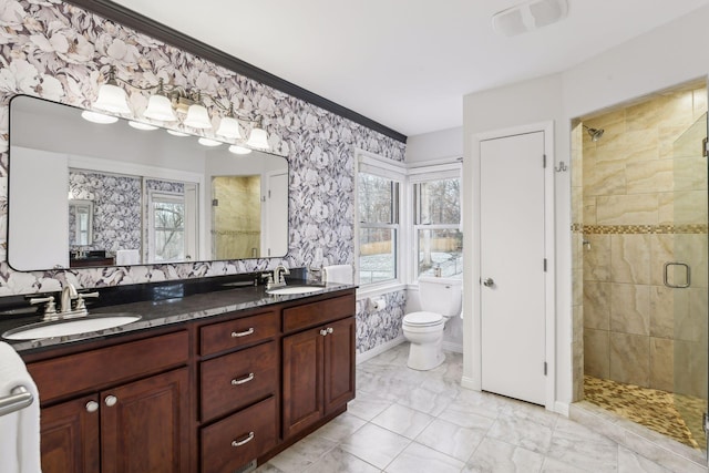 bathroom featuring a healthy amount of sunlight, tiled shower, vanity, and toilet