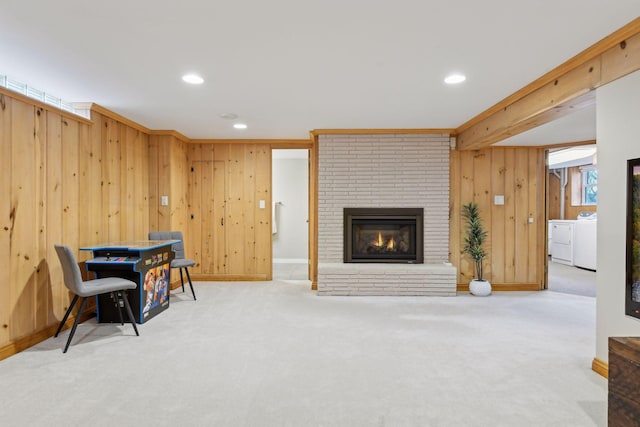 living area featuring a fireplace, washing machine and dryer, carpet flooring, and wood walls