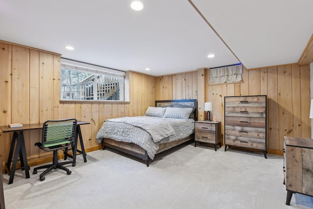 bedroom with light carpet and wooden walls