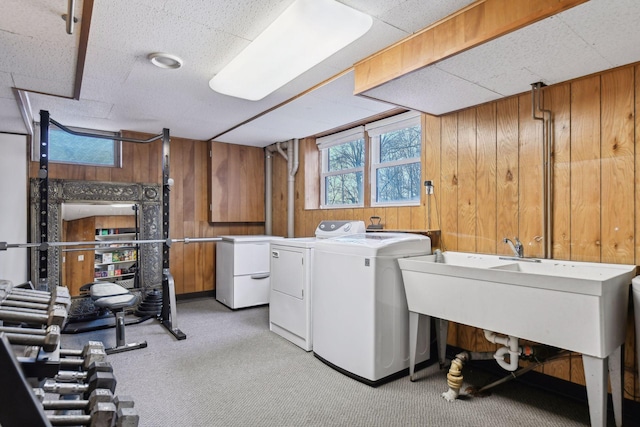 clothes washing area with light carpet, independent washer and dryer, and wooden walls