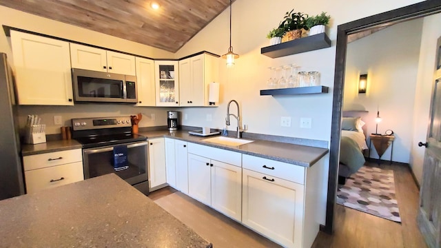 kitchen with open shelves, stainless steel appliances, glass insert cabinets, white cabinets, and a sink