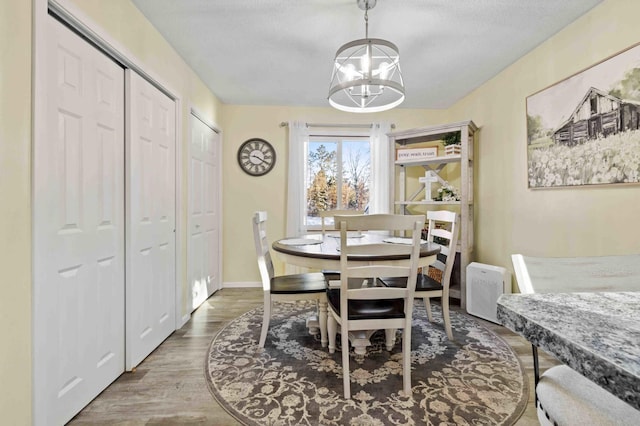 dining area featuring an inviting chandelier, wood-type flooring, and a textured ceiling