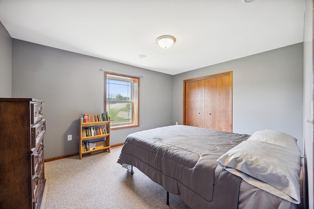 bedroom featuring a closet, light colored carpet, and baseboards