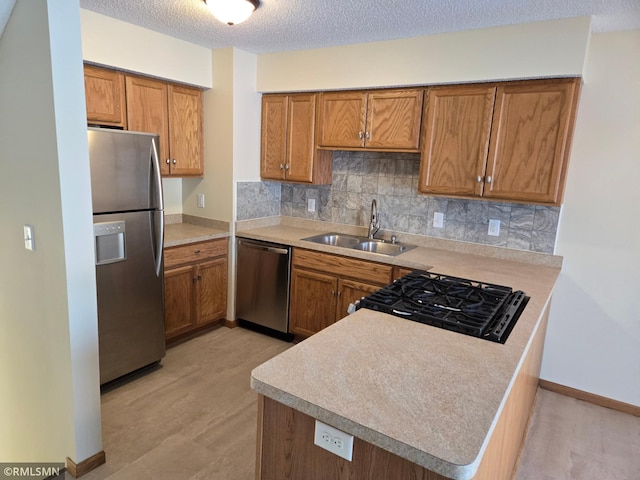 kitchen with kitchen peninsula, stainless steel appliances, sink, a textured ceiling, and decorative backsplash