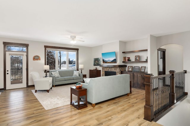 living room featuring a fireplace, ceiling fan, and light hardwood / wood-style flooring