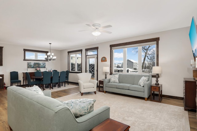 living room with ceiling fan with notable chandelier and light wood-type flooring