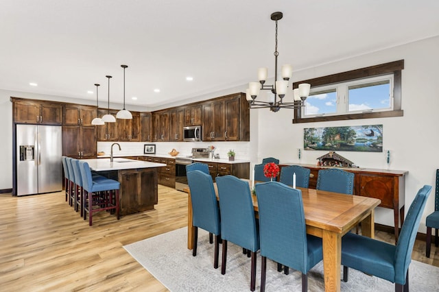 dining room with a notable chandelier, sink, and light hardwood / wood-style floors