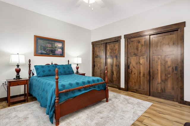 bedroom featuring hardwood / wood-style flooring, two closets, and ceiling fan