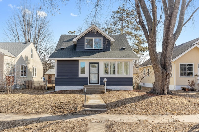 bungalow-style home with entry steps, a shingled roof, and fence