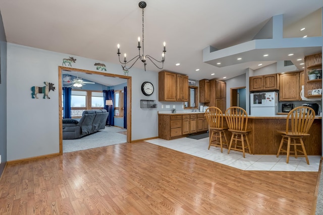 kitchen with a breakfast bar area, white appliances, lofted ceiling, light hardwood / wood-style floors, and kitchen peninsula