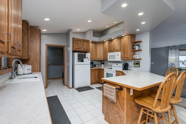 kitchen featuring white appliances, light tile patterned flooring, sink, a kitchen bar, and kitchen peninsula