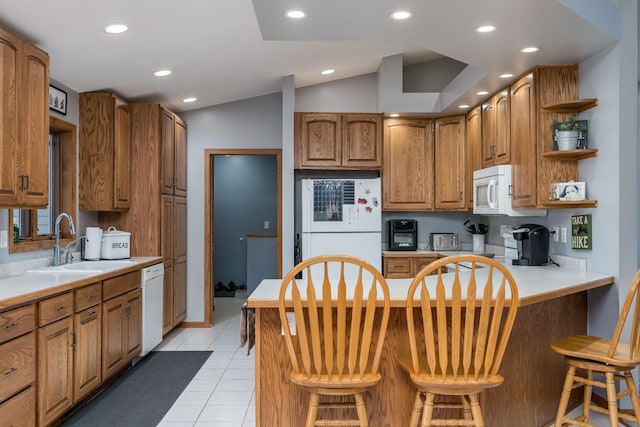 kitchen with white appliances, lofted ceiling, a breakfast bar, sink, and light tile patterned flooring