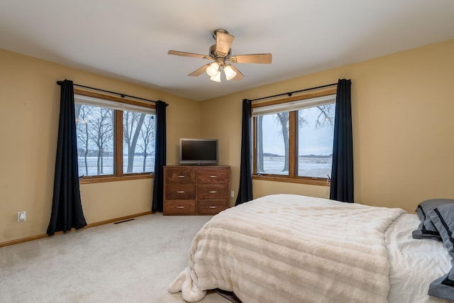 bedroom featuring ceiling fan, multiple windows, and light colored carpet