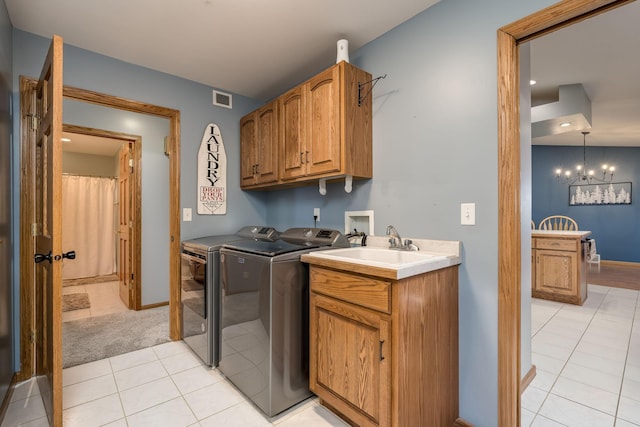 laundry area with a notable chandelier, light tile patterned floors, separate washer and dryer, and cabinets