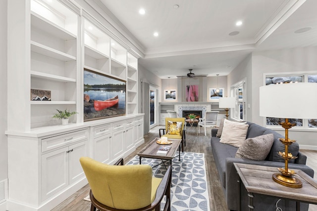 living room featuring ornamental molding, built in shelves, ceiling fan, and wood-type flooring