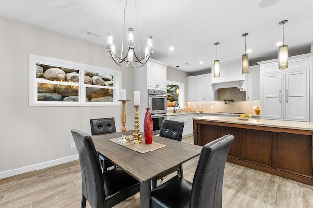 dining room featuring sink, an inviting chandelier, and light hardwood / wood-style flooring