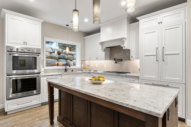 kitchen featuring sink, a center island, white cabinetry, pendant lighting, and stainless steel appliances