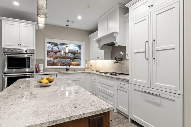 kitchen with appliances with stainless steel finishes, decorative light fixtures, sink, and white cabinetry