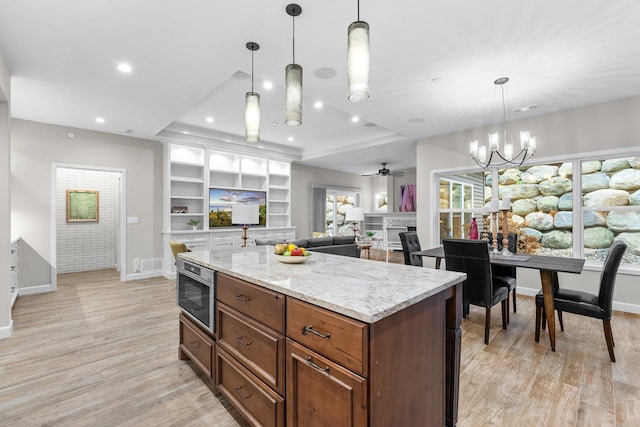 kitchen featuring decorative light fixtures, light wood-type flooring, and light stone countertops