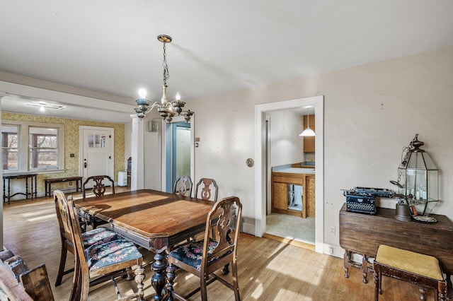 dining room featuring baseboards, light wood finished floors, and an inviting chandelier