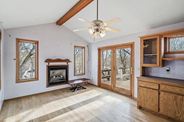 unfurnished living room with vaulted ceiling with beams, light wood-style flooring, a fireplace, and a wealth of natural light