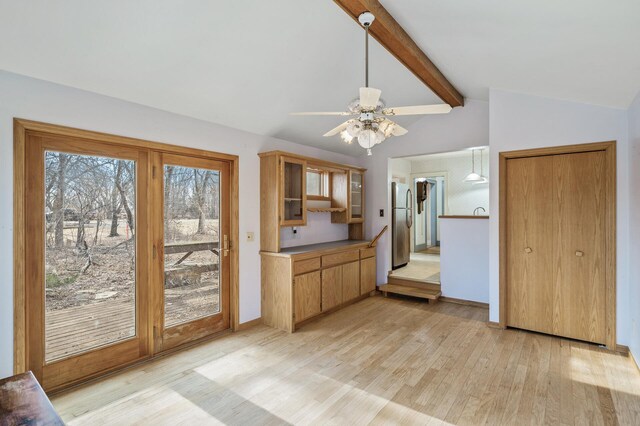 kitchen with vaulted ceiling with beams, light wood-style flooring, glass insert cabinets, freestanding refrigerator, and baseboards