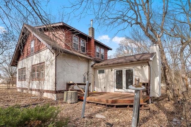 back of house with a deck, central AC, a chimney, and stucco siding