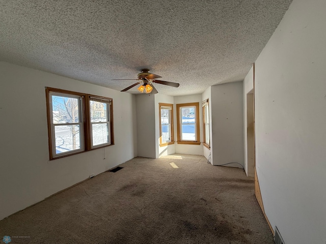 carpeted spare room with ceiling fan and a textured ceiling