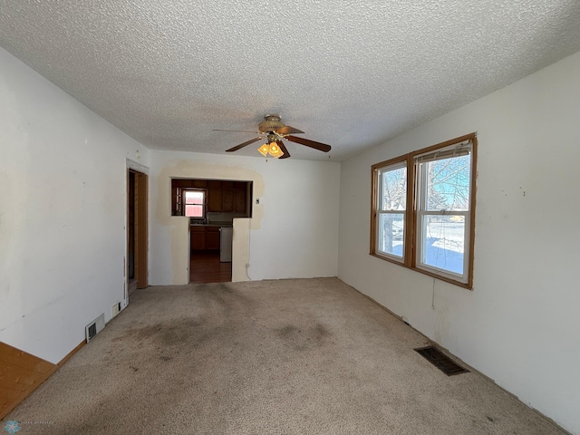 unfurnished living room featuring ceiling fan, carpet, and a textured ceiling