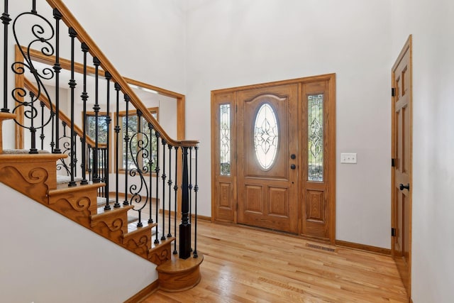 foyer entrance with a towering ceiling and light hardwood / wood-style floors