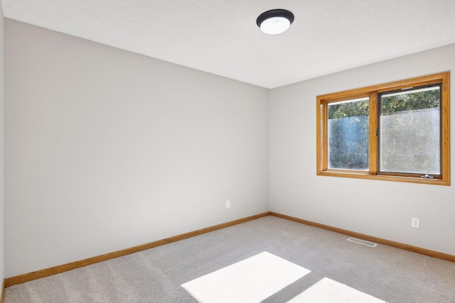 carpeted empty room featuring a textured ceiling