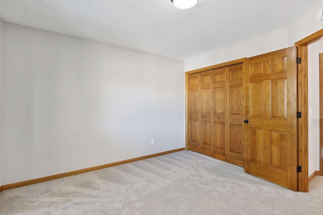 unfurnished bedroom with a closet, light carpet, and a textured ceiling