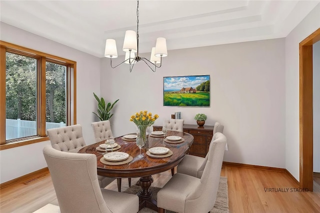 dining area with light hardwood / wood-style floors and a chandelier