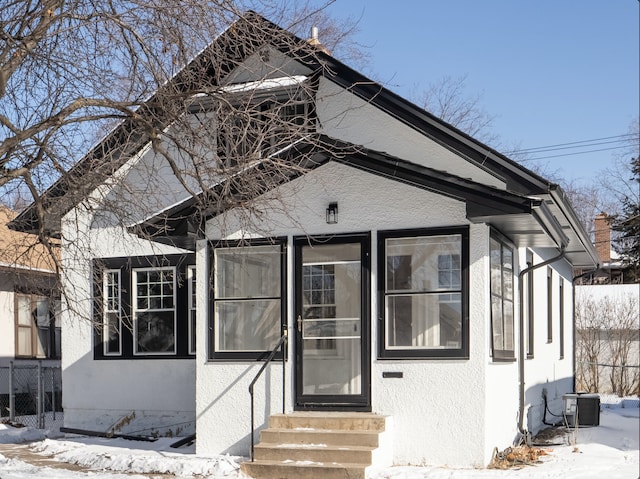 view of front facade with entry steps, central air condition unit, fence, and stucco siding